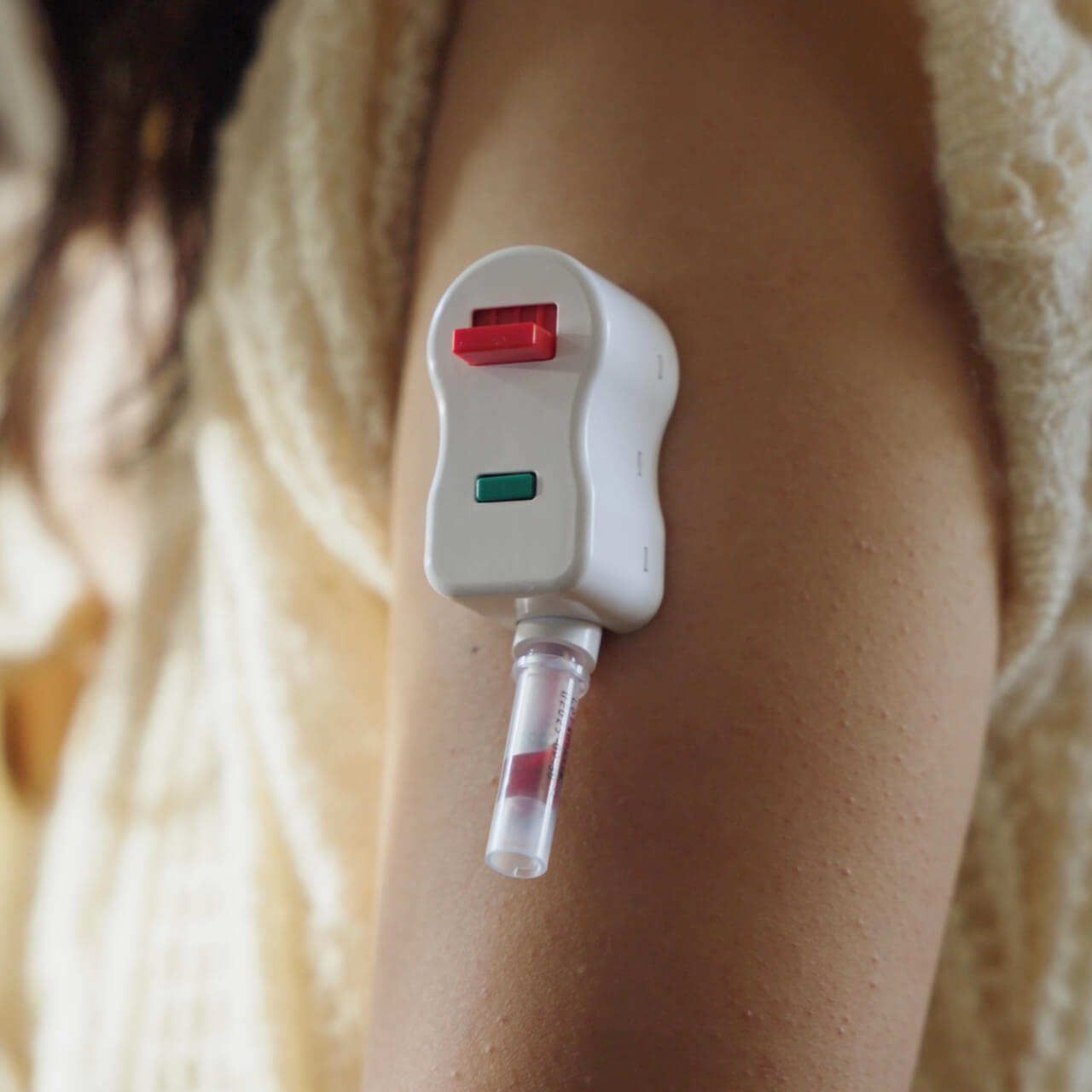A woman wearing the SiPhox EasyDraw collector on her outer upper arm